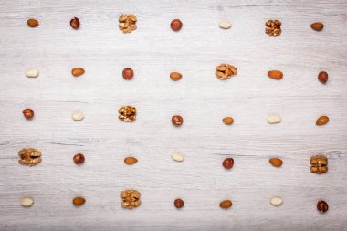 fındık, badem, fındık ve jöle şekerler simetrik satırlarla kaplı bir ışık ahşap yüzeyde. Şeker ve fındık güzel arka plan.