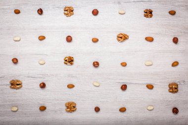 fındık, badem, fındık ve jöle şekerler simetrik satırlarla kaplı bir ışık ahşap yüzeyde. Şeker ve fındık güzel arka plan.