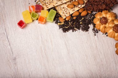 Çay bir ahşap yüzeyde bileşimi. saçılma çay, badem ve fındık. Yeşil, siyah çay. Tanımlama bilgileri ve sakızlı şeker. Kopya alanı ile üstten görünüm.