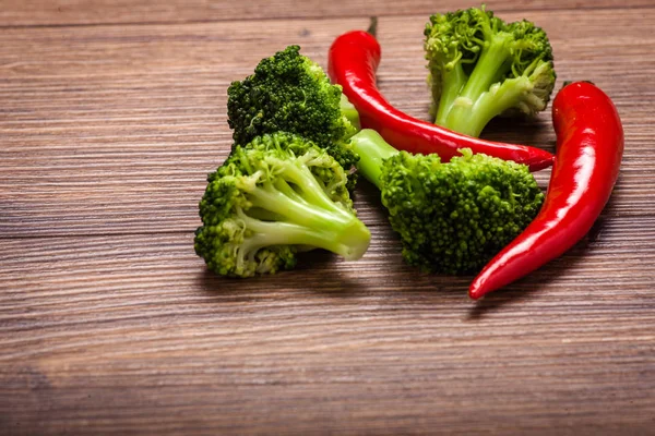 Green broccoli, red chili on a wooden surface — Stock Photo, Image