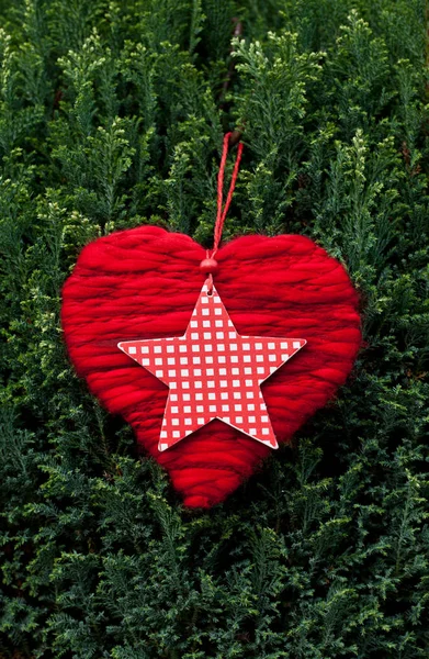 Corazón de lana y estrella de Navidad a través de verde —  Fotos de Stock