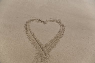 Bir plajda kuma çizilmiş bir kalp şekli