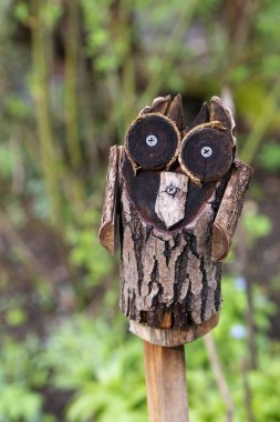 Bir kır bahçesindeki direğin üzerinde ağaçtan yapılmış tuhaf bir baykuş.
