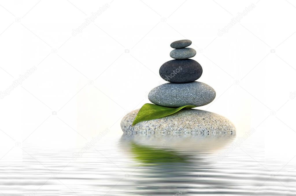 Balanced stone cairn and green leaf reflecting in water