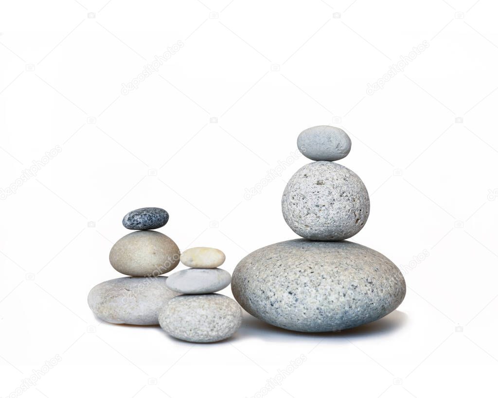 group of three balanced pebble stone cairns across a white background