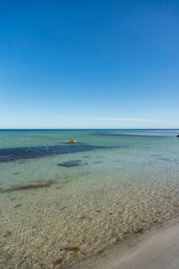 Issız, sığ kumlu kumlu sahil berrak bir bahar gününde açık mavi gökyüzü ile birlikte Danimarka 'nın Bornholm adasına yaptığı gezide ele geçirildi.