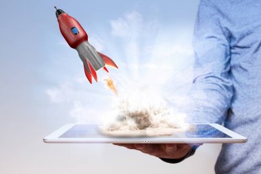 Mans hand with tablet pc and flying rocket.  clipart