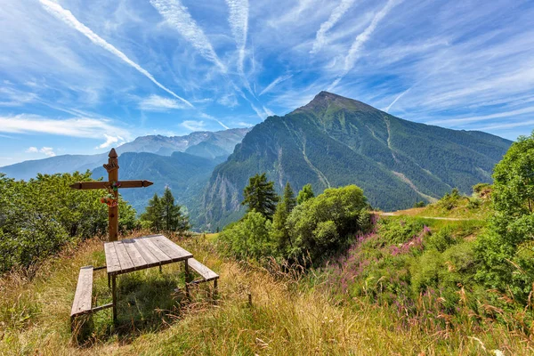Houten bankje met Kruis en Italiaanse Alpen in Piemonte, Italië. — Stockfoto