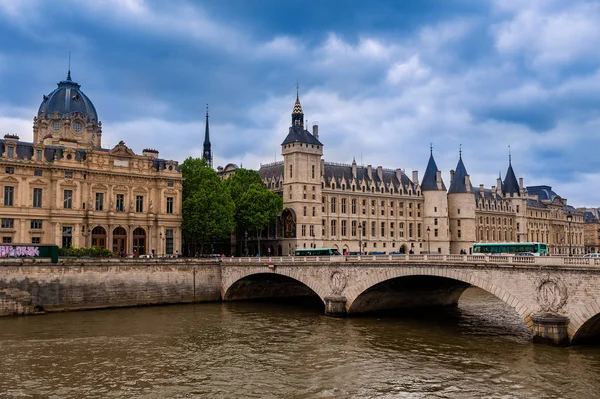 Conciergerie budynków i mostów nad Sekwaną pod zachmurzone niebo i — Zdjęcie stockowe