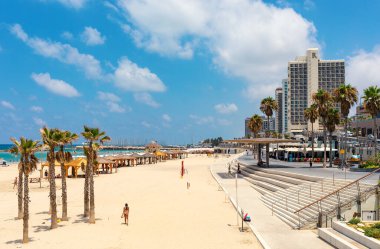 TEL AVIV, ISRAEL - 19 Temmuz 2017: Akdeniz kıyı şeridi boyunca halk plajındaki insanlar ve Tel Aviv 'deki modern otellerle gezinti - İsrail' in en kalabalık ikinci şehri, ülkenin finans ve teknoloji merkezi.