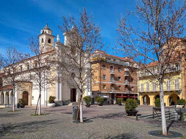 意大利北部皮埃蒙特阿尔巴蓝天下的鹅卵石小镇广场和白色教区教堂 — 图库照片