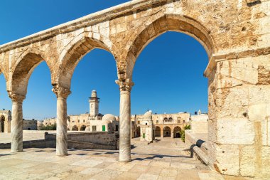 İsrail 'in Kudüs kentindeki Tapınak Dağı' ndaki antik taş kemerlerin arasından mavi gökyüzü altında tipik evler ve minareler görülüyor..