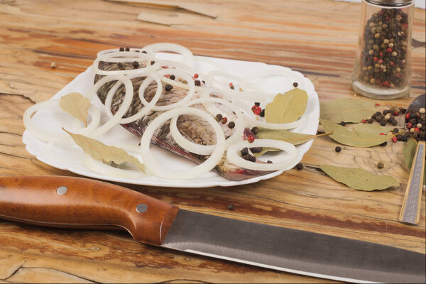 Fish on a white plate on a wooden background with seasoning