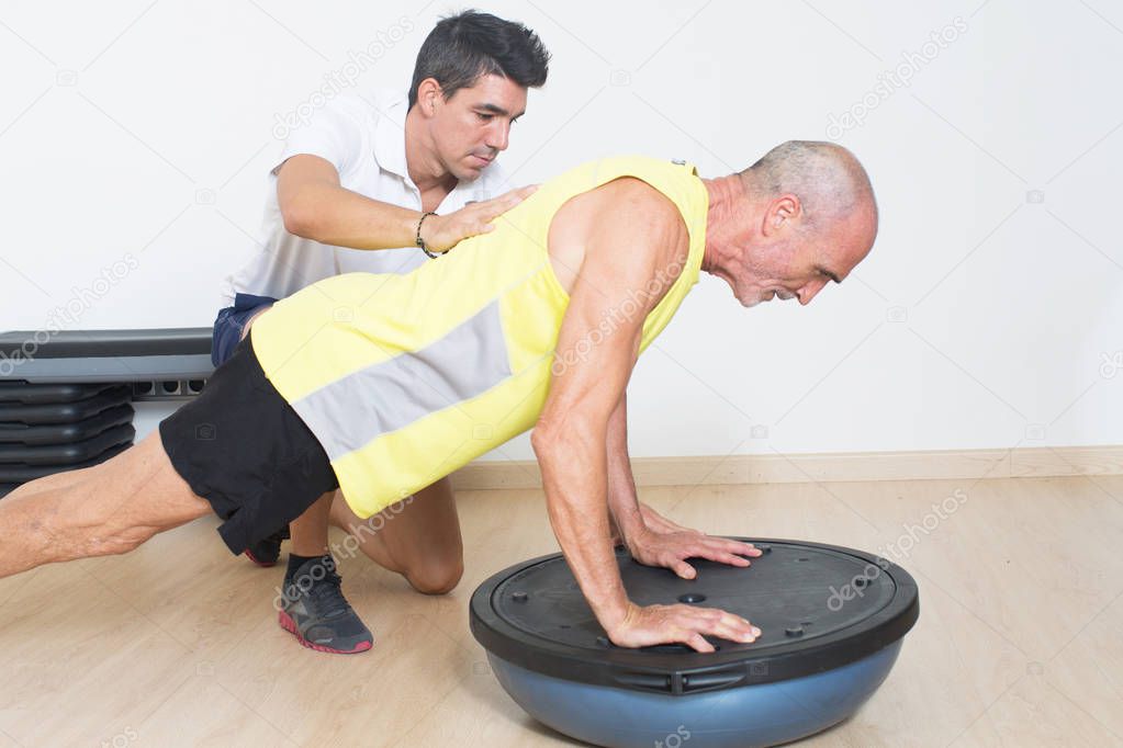coach helps senior with suspension push-up training
