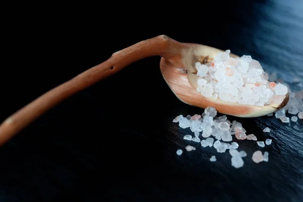 Himalayan salt on a wooden spoon with black background — Stock Photo, Image
