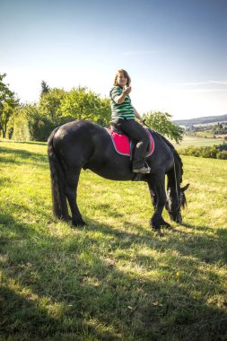 Güzel genç kadın onun siyah ata biniyor 
