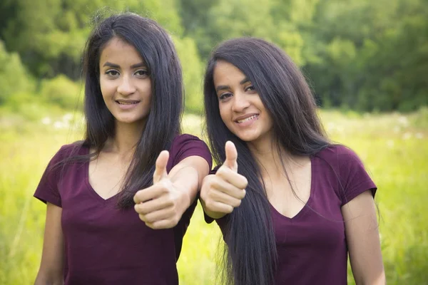 Portrét šťastné sestry dvojčata ukazuje palec — Stock fotografie