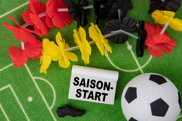 セゾンドイツ語で始まるということは シーズン開始を意味する ドイツの国旗とカレンダーの色の花のネックレスとサッカーボール — ストック写真