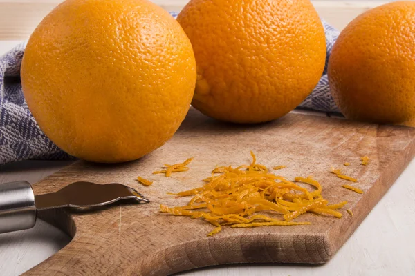 Pomerančové kůry na dřevěné desce s zester — Stock fotografie