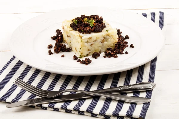 Картофельное пюре и черный пудинг на тарелке — стоковое фото