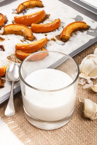 Geroosterde pompoen wiggen op een bakken lade en een glas yoghurt gar — Stockfoto