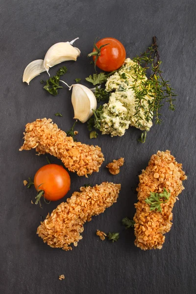 Deep fried oatmeal breaded chicken breast strips on slate — Stock Photo, Image