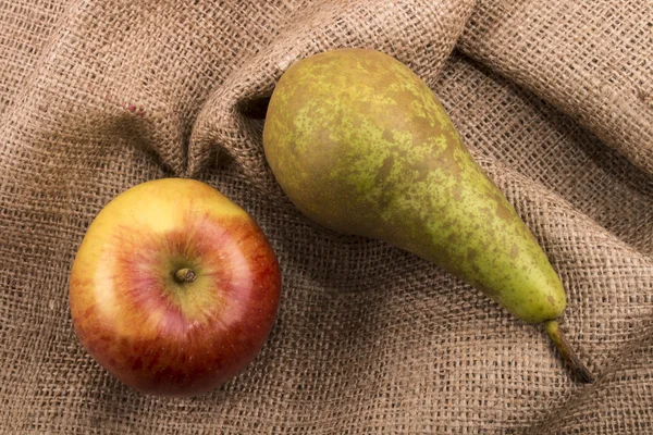 Красный яблоко и зеленая груша на джуте — стоковое фото