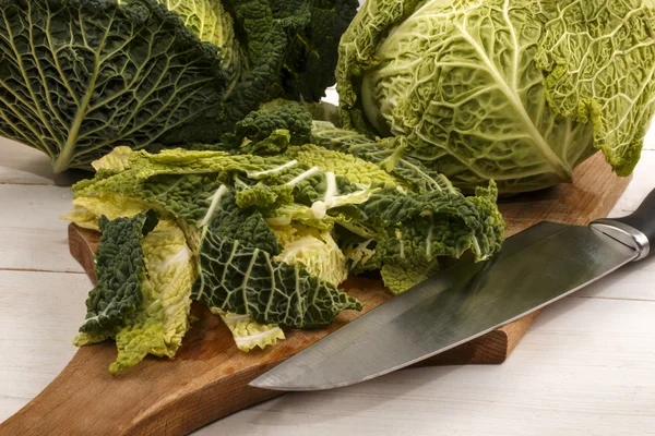 Savoy cabbage is cut on a wooden board in small strips and prepa — Φωτογραφία Αρχείου