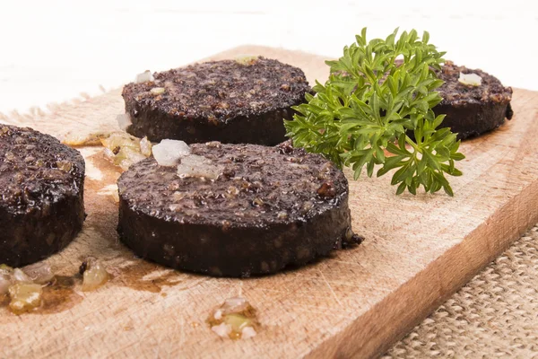 Grilled irish black pudding with parsley on a wooden board — Stock fotografie