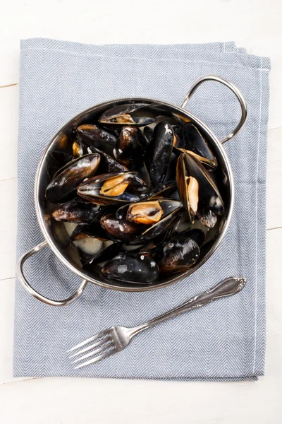 Boiled mussels in a metal bowl and fork on a light blue cloth — Stock Photo, Image