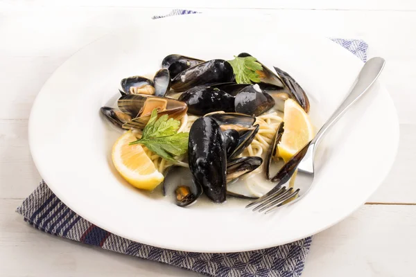 Mejillones, espaguetis, limón y perejil en un plato —  Fotos de Stock