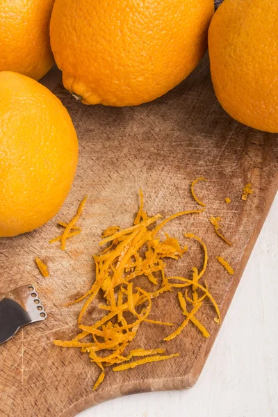 Laranja fresca e zester para obter raspas de laranja em um velho woode — Fotografia de Stock