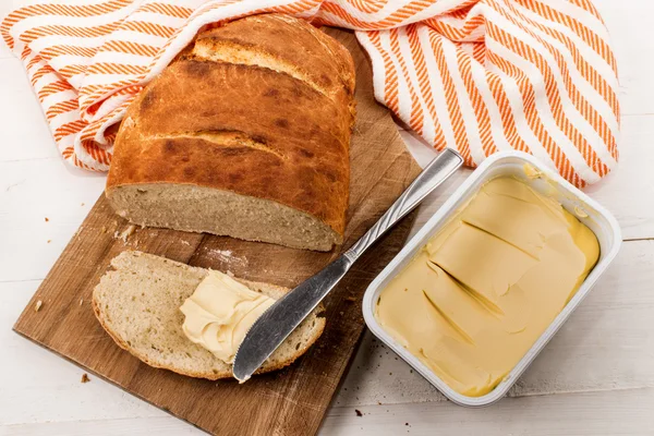 Rebanada de pan casero al horno con margarina en una tabla de cortar —  Fotos de Stock