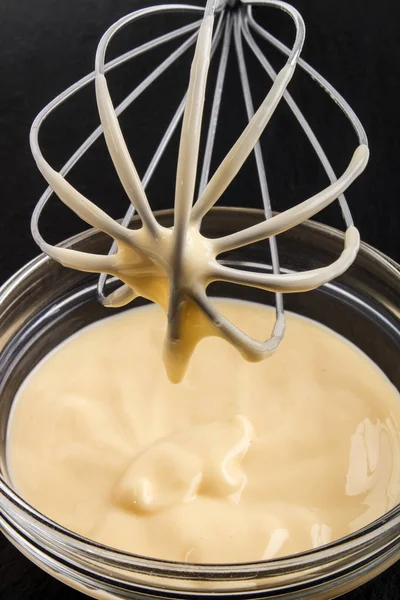 Whisk and bowl with homemade custard — Stock Photo, Image