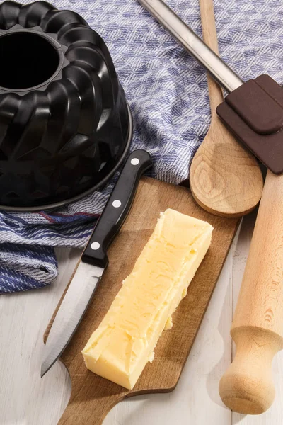 Bakken gebruiksvoorwerpen en een bar boter op houten bord — Stockfoto