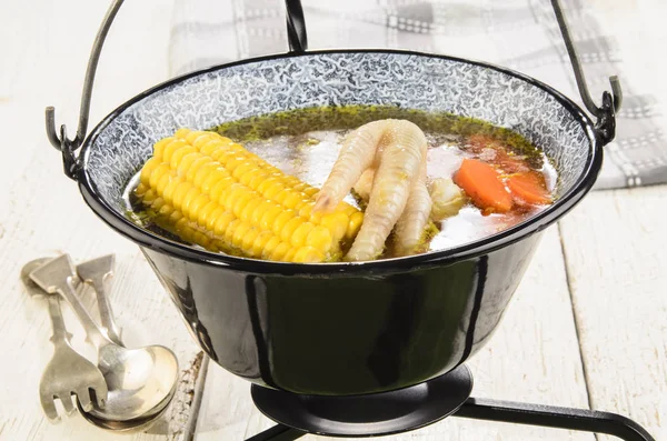 Hungarian chicken soup in a black kettle — Stock Photo, Image