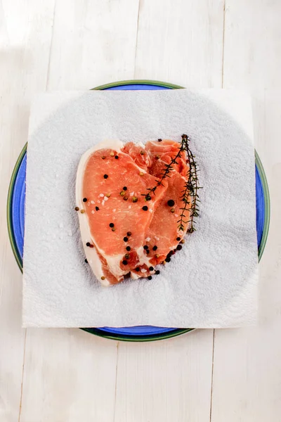 Pork loin steak with thyme, peppercorn and coarse salt on plate — Stock Photo, Image