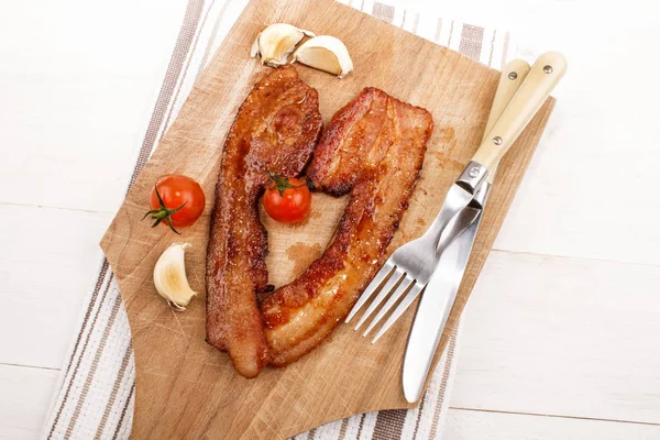 Grillad kryddig bacon med tomat och vitlök på en träskiva — Stockfoto