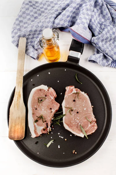 Raw pork chops on a pan with rosemary, coarse salt and peppercor — Stock Photo, Image