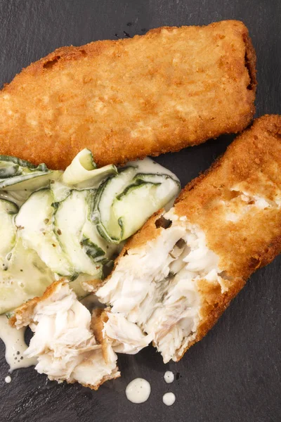 Breaded cod and fresh cucumber salad on slate — Stock Photo, Image