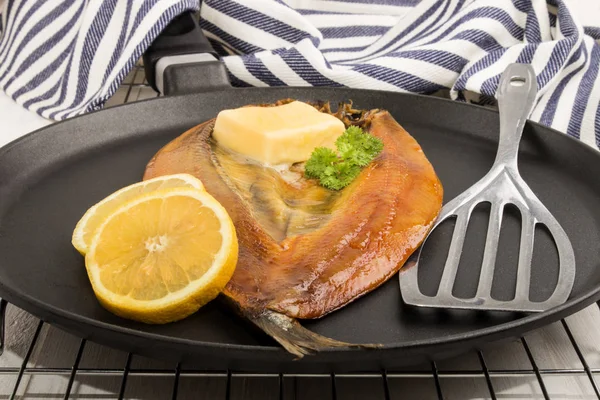 Копчений кіппер з лимоном, маслом і петрушкою на сковороді — стокове фото