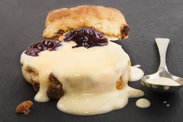 Raisin scone with fresh custard on slate — Stock Photo, Image