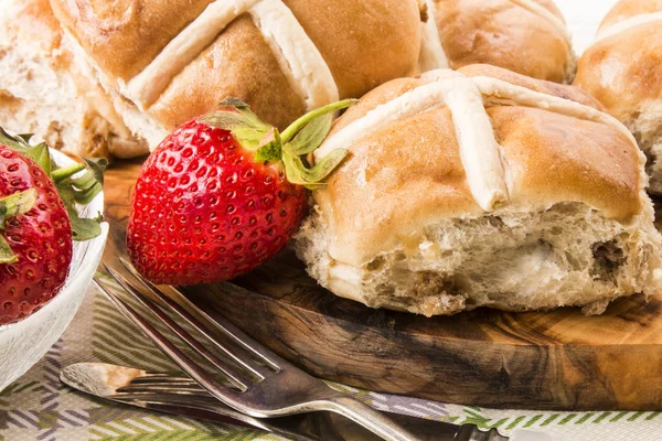Hot cross buns and sweet strawberries on a wooden board — Stock Photo, Image