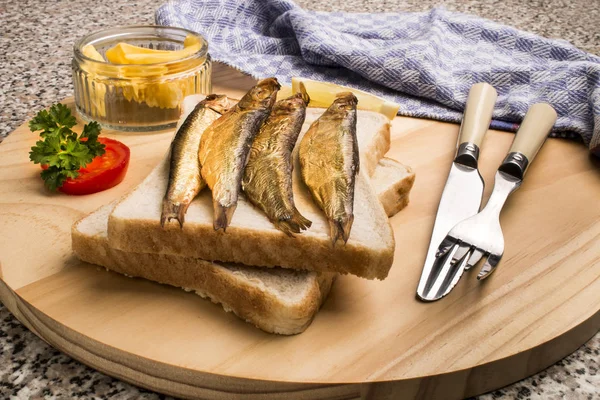Golden brown smoked sprats on wooden board — Stock Photo, Image