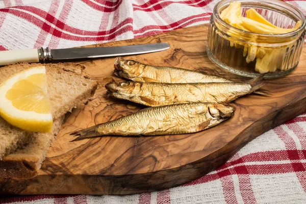 Sprats fumés brun doré sur planche de bois — Photo