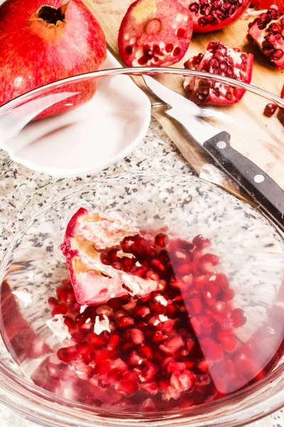 Pomegranate seeds are separated from the fruit in a bowl filled — Stock Photo, Image
