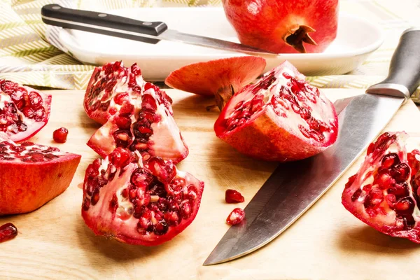 Sliced pomegranate with knife on a wooden board — Stock Photo, Image