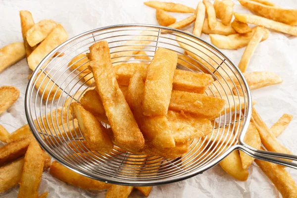 Batatas fritas francesas frescas de uma fritadeira em uma peneira — Fotografia de Stock
