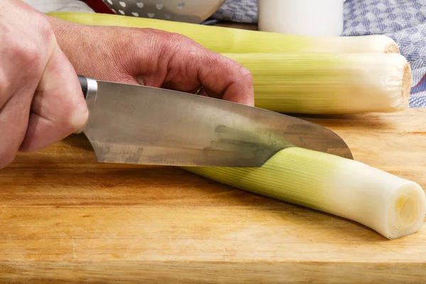 Žena připravuje pórek s kuchyňským nožem — Stock fotografie