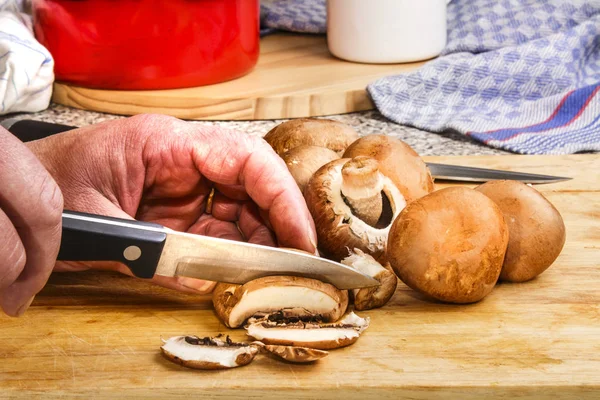 Vrouwelijke chef-kok is kastanje champignons in plakjes snijden — Stockfoto